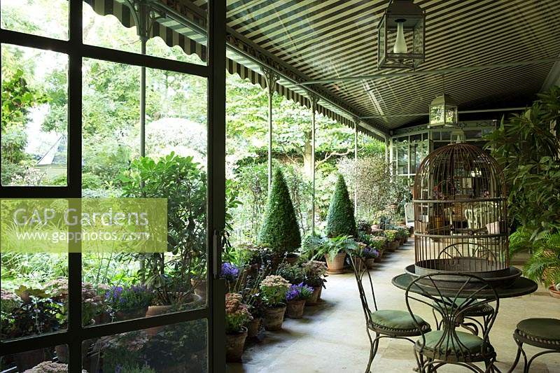 Deux vérandas ombragées relient l'espace extérieur dominé par des pots de fleurs violettes préférés de Pierre Berge