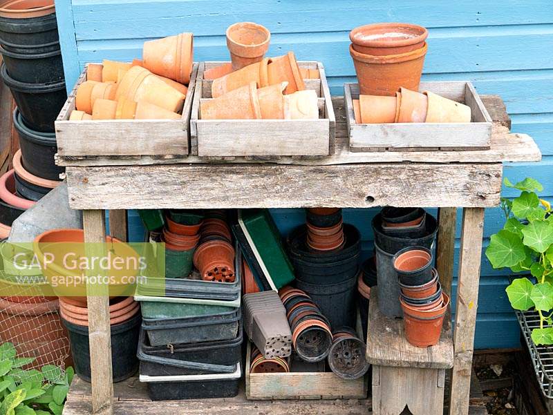 Pots en terre cuite et pots en plastique stockés à l'extérieur sous l'ancien banc.