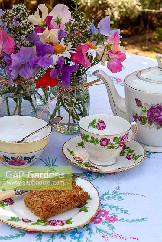 Pots de petits pois, lavande, marguerites Marguerite et marjolaine comme décorations de table avec réglage pour le thé