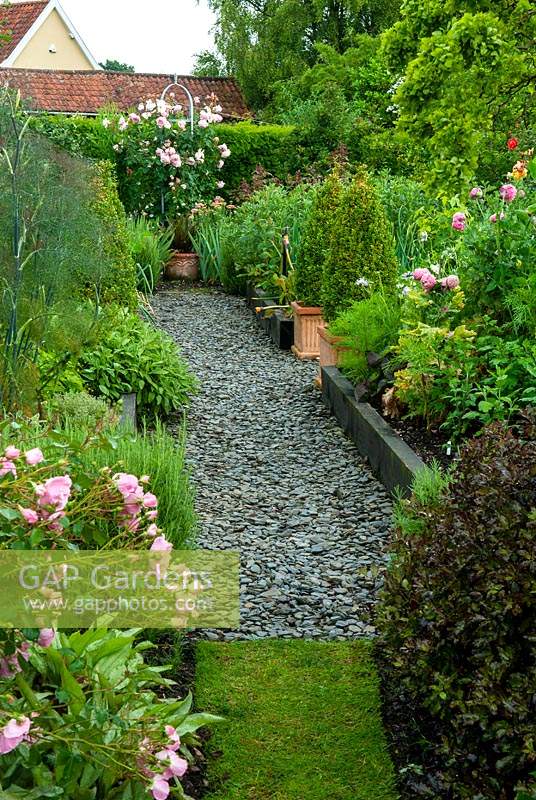 Parterres de fleurs surélevés et pots d'herbes, d'arbustes et de plantes vivaces, avec chemin de copeaux d'ardoise menant à l'escalade rose rose dans l'obélisque de métal - Journée des jardins ouverts, Double Street, Framlingham, Suffolk