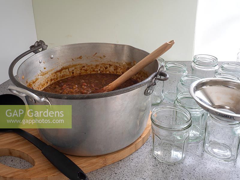 Ajout de chutney de tomates vertes dans des pots de cornichons propres