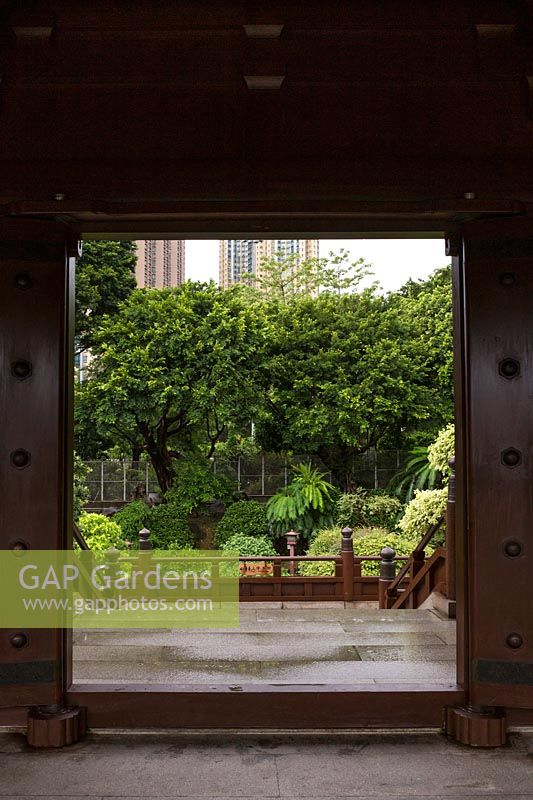 Vue à travers une porte de la passerelle couverte autour de la cour de l'étang de lotus, à un petit jardin latéral