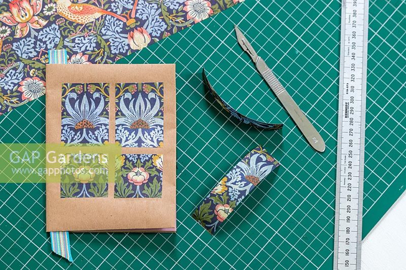 Faire des décorations en papier d'emballage sur un livre sur un banc de travail avec tapis de coupe, règle en métal et couteau artisanal