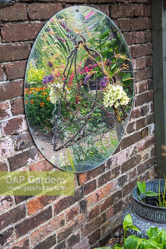 Sur une paroi latérale, un miroir en forme de dôme reflète des images déformées de fleurs dans le parterre central.
