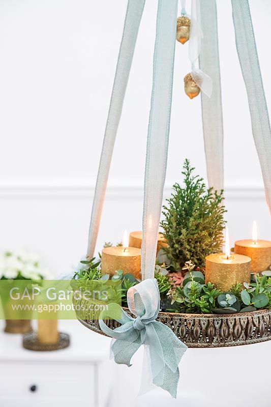 Arrangement de l'Avent suspendu avec bougies en or, sapin de Noël miniature et feuillage d'eucalyptus et de Hebe