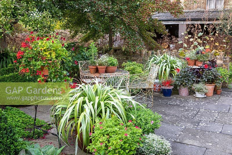 Meubles de jardin ornés avec une collection de pots sur une cour pavée