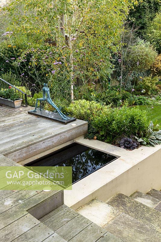 Jardin de ville à faible entretien - vue depuis une terrasse en bois surélevée avec piscine réfléchissante