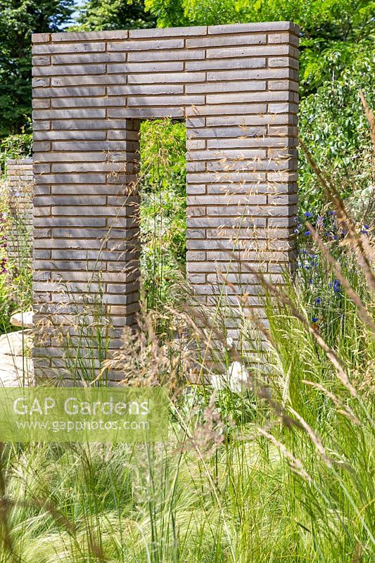 Jardin avec graminées ornementales divisé par des colonnes et des murs de pavés en brique de Belgique. Jardin du sanctuaire RHS - Festival des fleurs de Hampton Court 2019