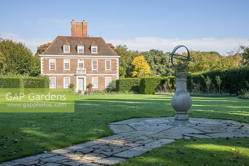 Armillaire sur piédestal en pierre à côté d'une pelouse devant une maison de Lutyens.