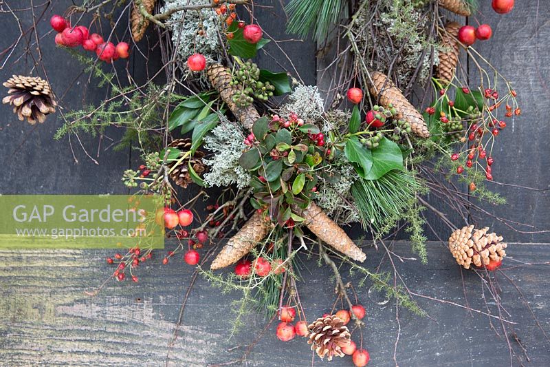Détail de la couronne de Noël rustique faite avec un mélange d'églantier, de pommes sauvages, de pommes de pin et de feuillage. Stylisme: Marieke Nolsen