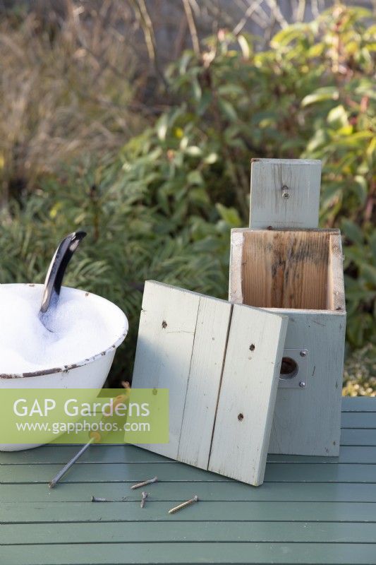 Bird Box sur table avec couvercle retiré prêt pour le nettoyage avec un désinfectant et de l'eau en hiver prêt pour la nidification des oiseaux au printemps