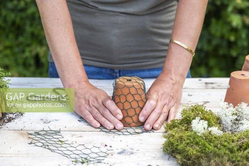 Femme poussant du grillage sur un petit pot en terre cuite pour façonner