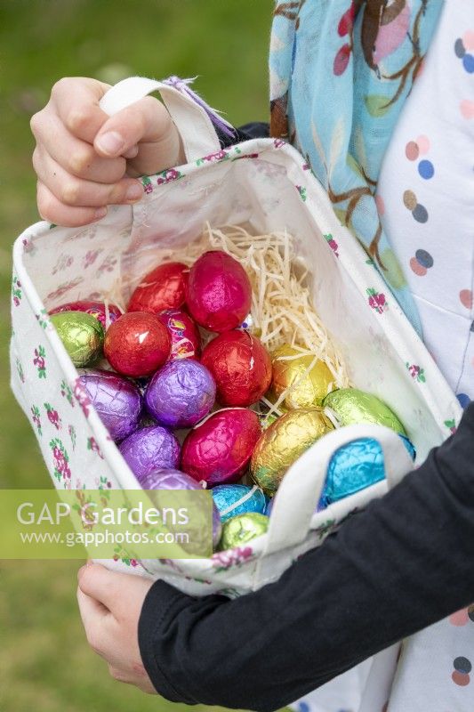 Petite fille participant à une chasse aux œufs de Pâques dans un jardin