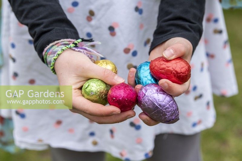 Enfant tenant des oeufs en chocolat colorés à Pâques