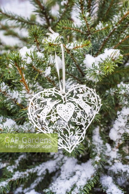 Coeur en filigrane de papier blanc sur l'arbre de Noël enneigé
