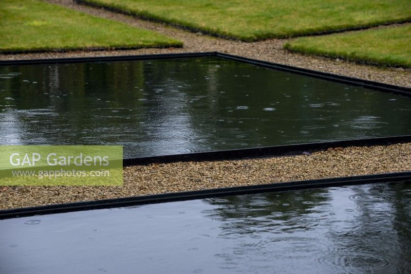 Piscine réfléchissante noire entourée de gravier dans le jardin à l'italienne à Thenford Arboretum