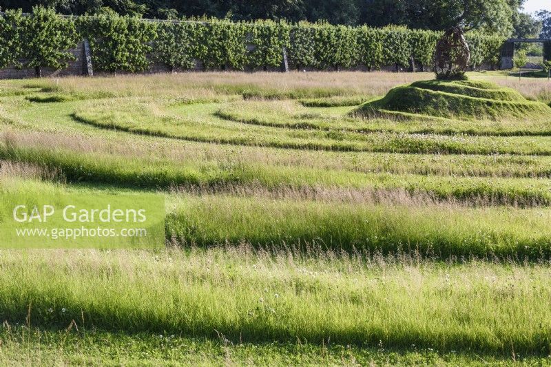 Labyrinthe d'herbe avec un monticule en spirale en son centre surmonté d'une poire faite d'outils de jardin rouillés au Gordon Castle Walled Garden, en Écosse en juillet