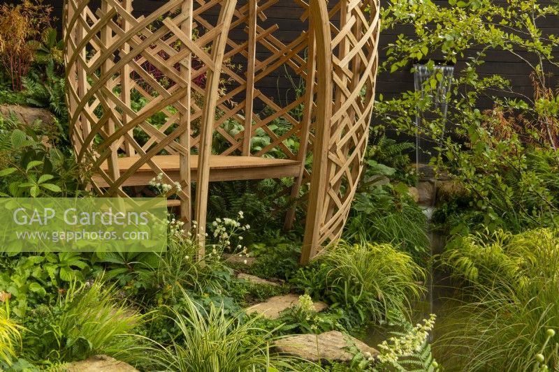 Une structure en grille de bambou stratifié avec un siège à côté d'une fontaine entourée d'une piscine dans un vallon boisé de Guangzhou en Chine : le jardin de Guangzhou a remporté le prix du meilleur jardin d'exposition.