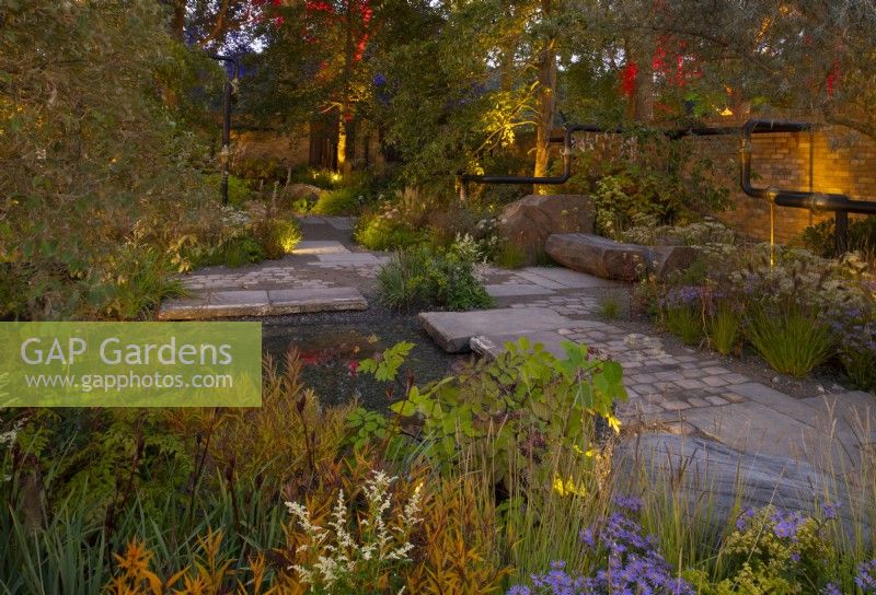 Le Jardin M et G, un espace urbain partagé avec des éclairages judicieusement placés accentuant les couleurs chaudes des plantations automnales entourant un petit bassin.