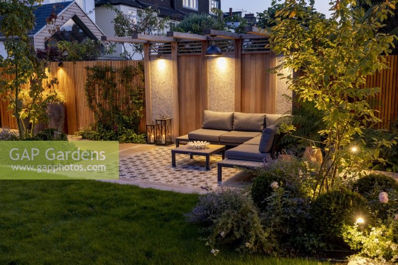 Jardin moderne avec terrasse et pergola la nuit avec éclairage