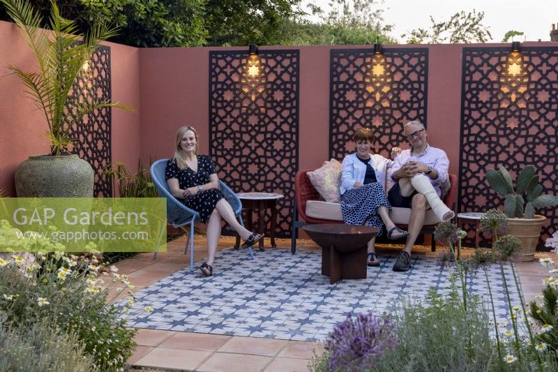 Détente en famille autour d'un foyer dans leur patio de jardin de style marocain