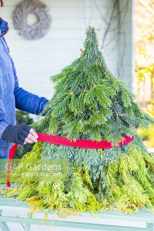 Femme enroulant un ruban autour des branches comme une ceinture