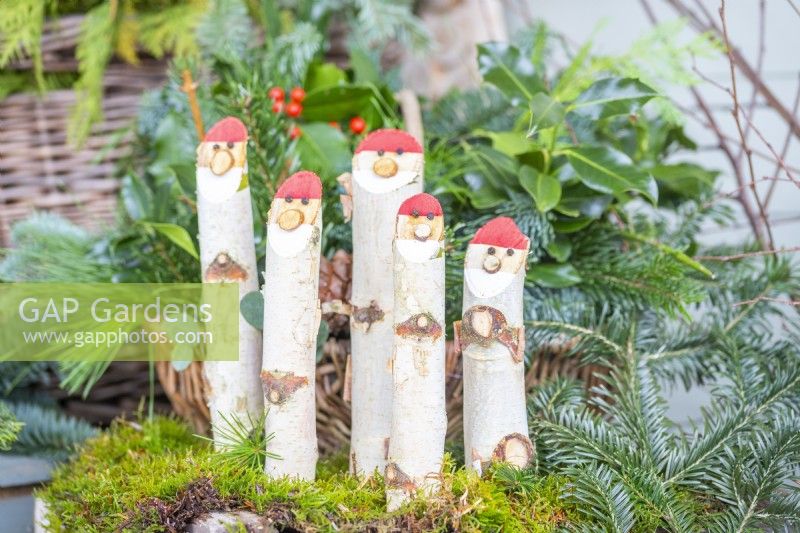 Bâton de bouleau Santas debout dans la mousse, entouré de feuillage