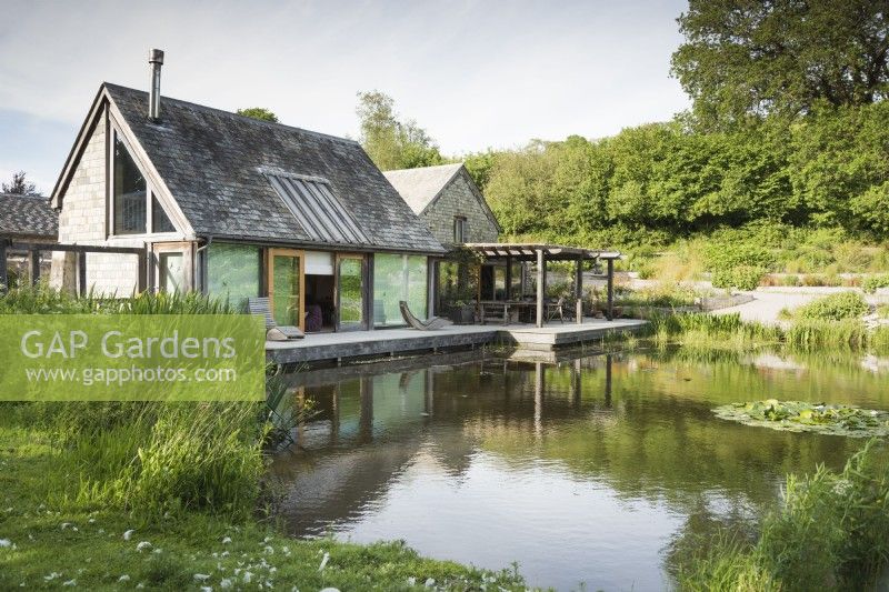 Maison au bord du lac conçue par Hugh Wray-McCann avec une terrasse en bois le long d'un côté à Am Brook Meadow dans le Devon.