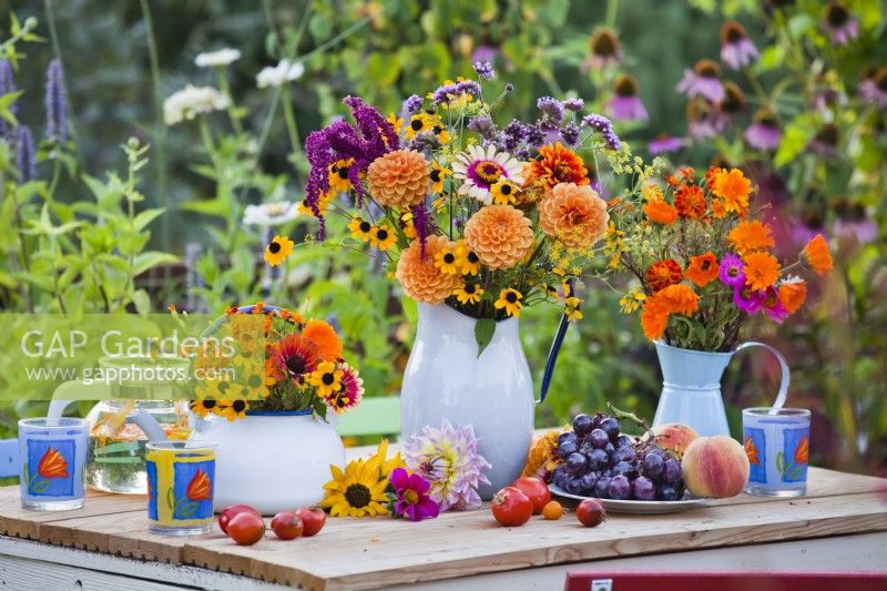 Présentoir de table avec bouquets de fleurs d'été avec dahlia, zinnia, rudbeckia, verveine et calendula dans des vases.