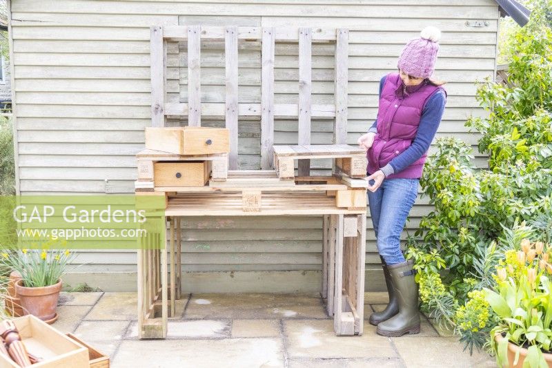 Femme plaçant des morceaux de bois sous des palettes plus petites pour faire de la place pour les tiroirs