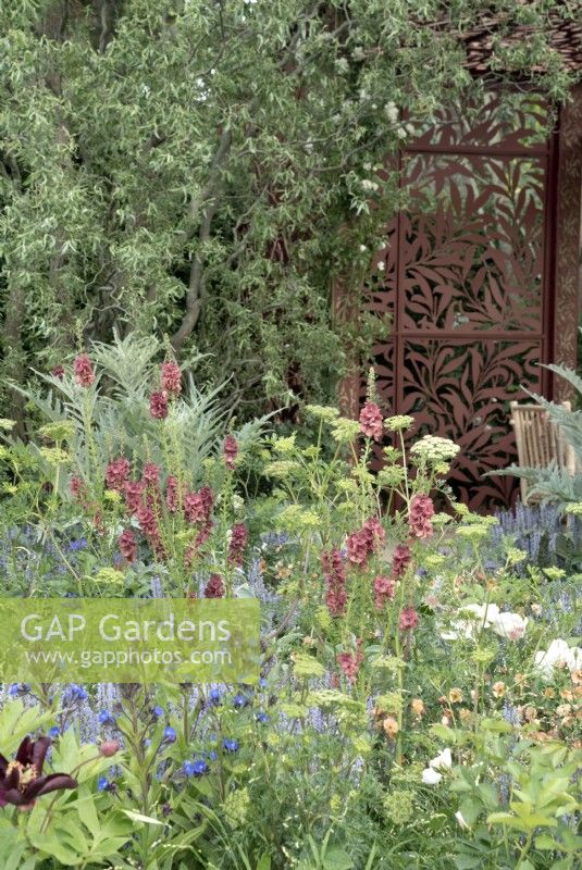 Jardin de style cottage romantique avec écran décoratif en forme de saule en métal.