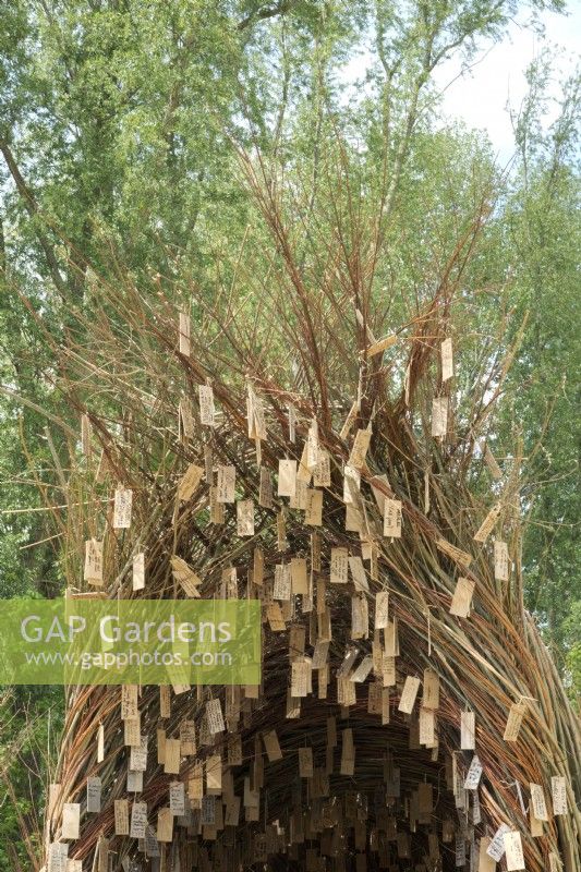 Arche de branches de saule remplie d'assiettes à souhaits en bois réalisées par l'artiste de la nature Will Beckers.