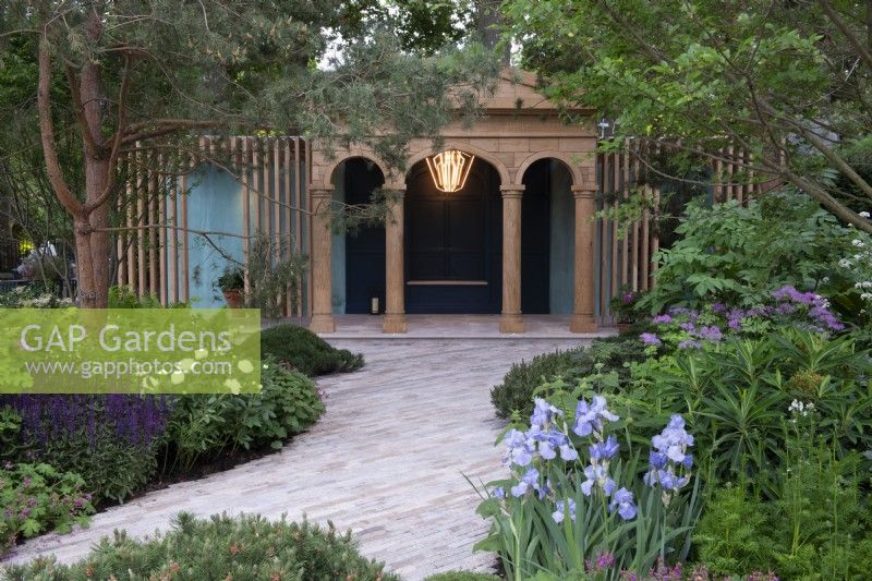 Pavés d'argile menant à un pavillon en chêne, Iris 'Jane Philips' au premier plan avec Euphorbia mellifera, Thalictrum et Salvia 'Caradonna' sous un Pinus sylvestris - The RNLI Garden, RHS Chelsea Flower Show 2022 - Gold Medal