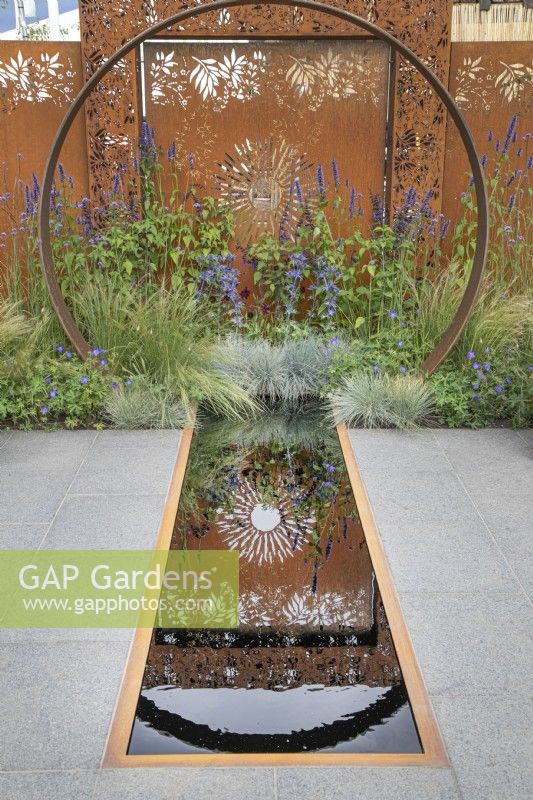 Moongate en acier Corten et reflets dans la piscine du jardin Sunburst au RHS Hampton Court Palace Garden Festival 2022