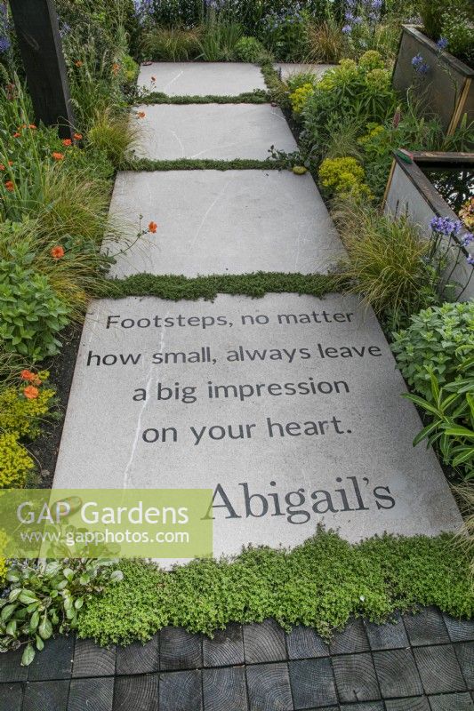 Chemin avec message bordé de plantes vivaces dans le jardin des pas d'Abigail au RHS Malvern Spring Festival 2022
