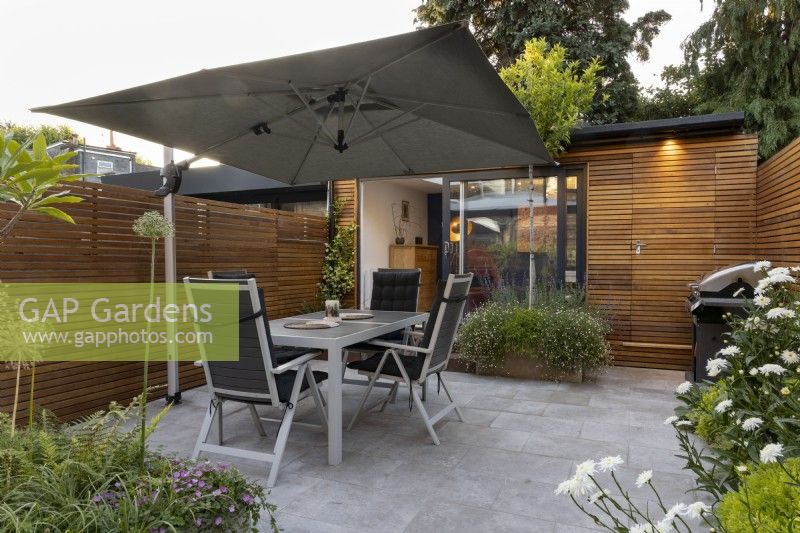 Jardin de nuit avec éclairage, vue sur patio vers office de jardin