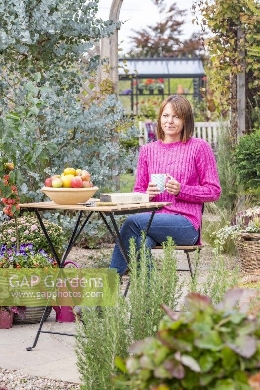 Femme assise à table dans un jardin avec une tasse de thé