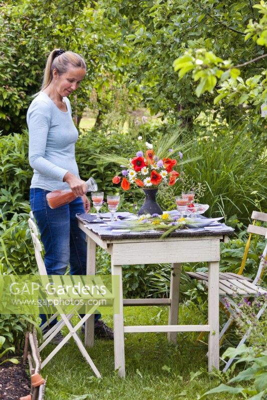 Femme installant une table pour un dîner en plein air.