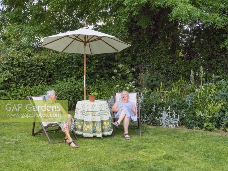 Deux femmes assises sur des transats discutant dans le jardin
