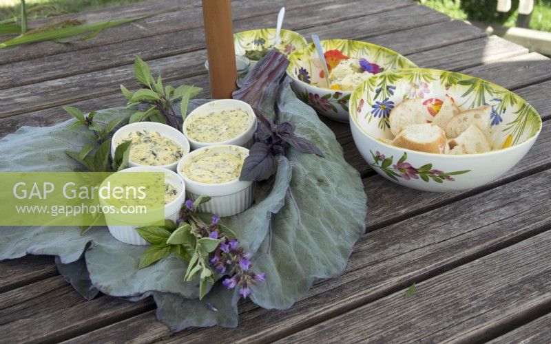 Beurre aux herbes fabriqué à partir d'herbes et de légumes récoltés par nos soins, servi avec une baguette sur une feuille de chou rouge.