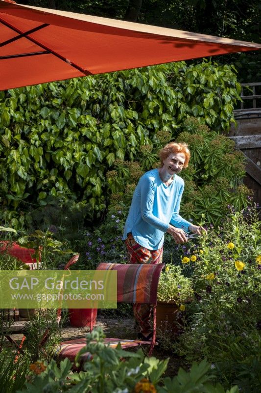 Propriétaire de jardin rangeant le parterre de fleurs dans son jardin de cottage de Londres, l'été