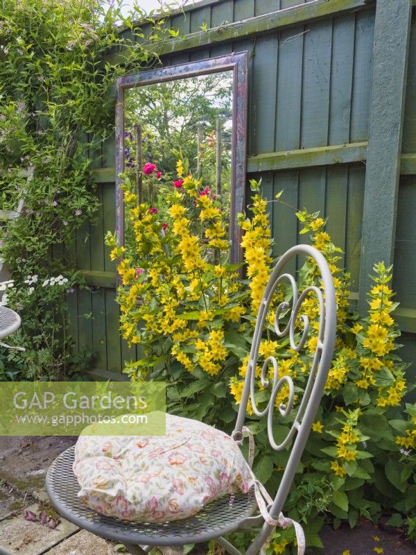 Réflexions de jardin dans un miroir encadré suspendu à une clôture de jardin