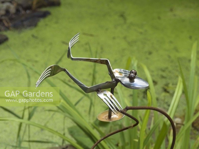 Fourchette et cuillère sculpture de grenouille par étang de jardin