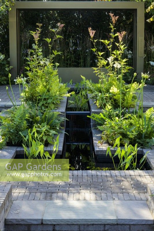Ruisseau d'eau dans un aménagement paysager dur - Macmillan Legacy Garden: Gift the Future garden au RHS Hampton Court Palace Garden Festival 2022