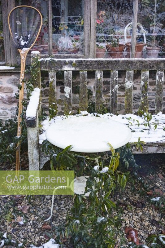 Table et banc enneigés dans un jardin en décembre.