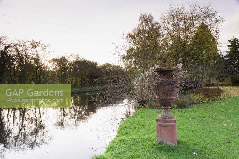 Urne en terre cuite à côté du canal qui fleurit le jardin de John Massey en octobre.