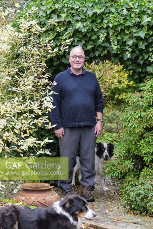 Homme avec deux chiens dans son jardin.