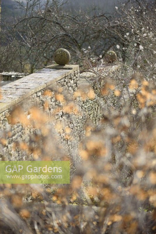 Murs avec sphères de pierre à Cotswold Farm Gardens en février.