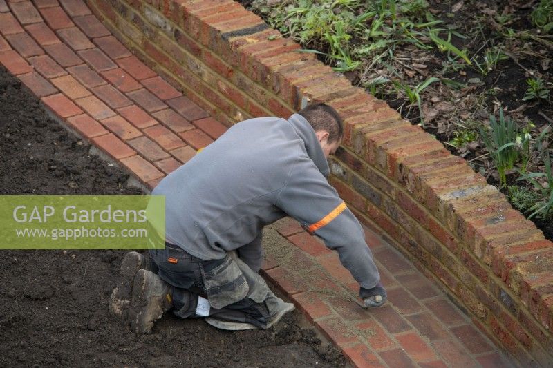 Un travailleur pointant les briques sur un chemin nouvellement construit lors de la rénovation d'un jardin de Londres.