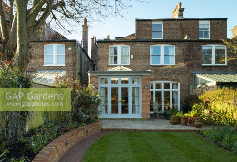 Un jardin londonien après une cure de jouvence avec un nouveau mur de briques, un chemin, une terrasse agrandie et un nouveau gazon.